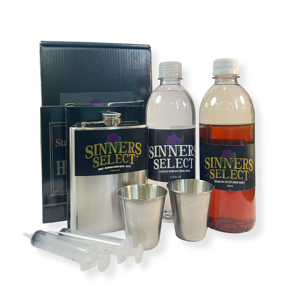 Sinners Select limestone water and honey bottles, flask, and shot glasses on a white background