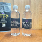 Two bottles of Sinners Select Water on a counter with a bag of Sinners Select Coffee in the background