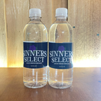 Two bottles of Sinner's Select water on a wooden surface.